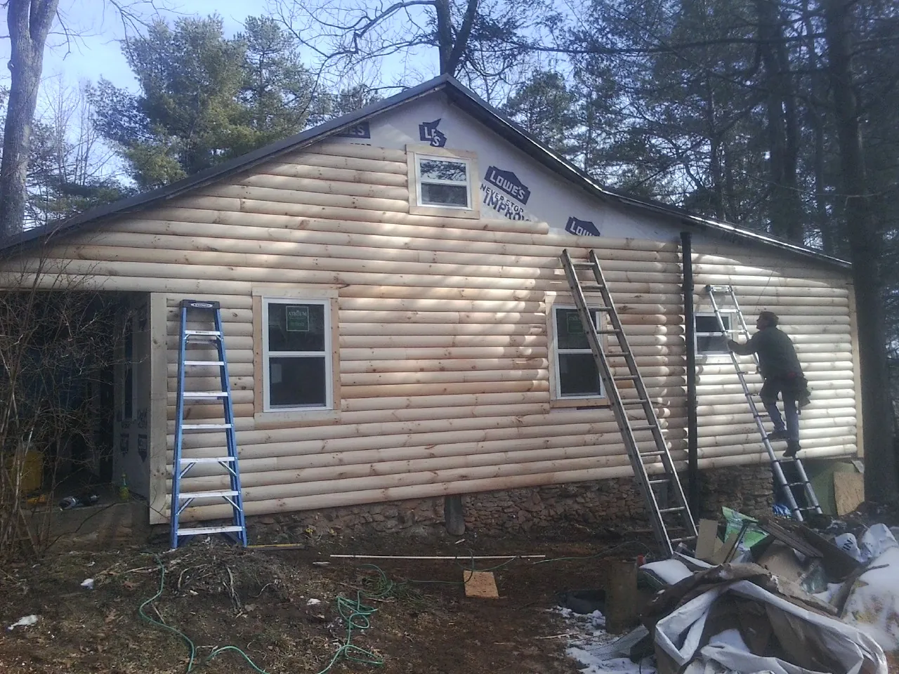 Ladders set against fresh log siding during an exterior remodel in Jewell