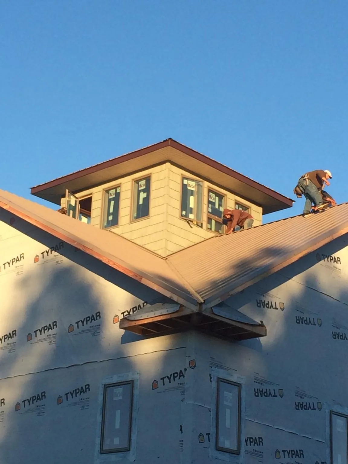 Roofers working around a rooftop cupola on a new metal roof at sunset — Roof Waterproofing in Jewell by Roofing Brothers